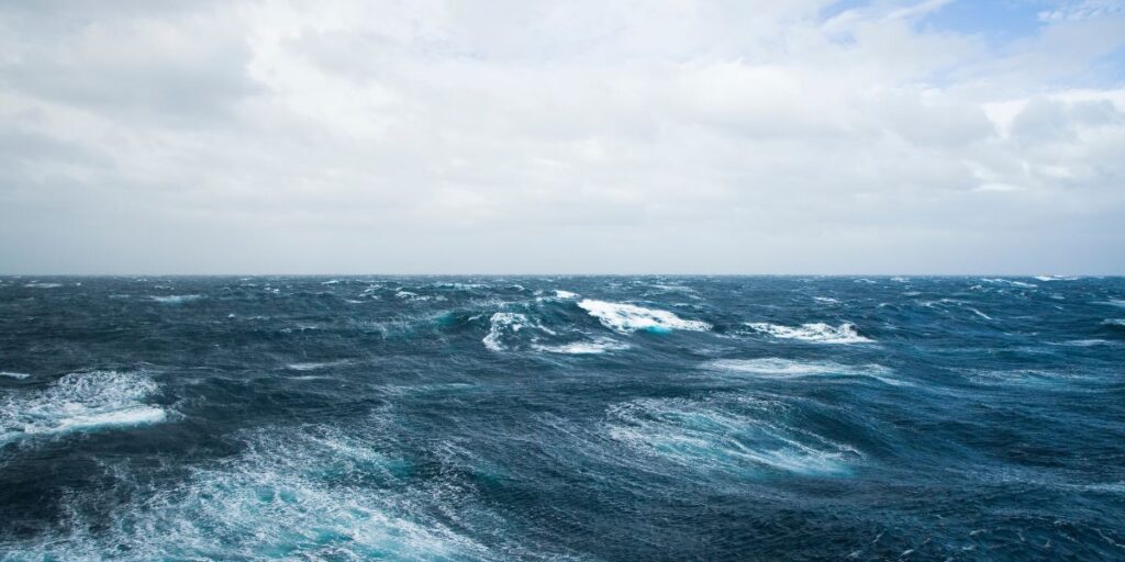 Vivid blues and whites clash as frothy waves of the Drake Passage roll under a cloudy sky, encapsulating the voyage's notorious volatility. Known as a rite of passage for Antarctic explorers, this image conveys the Drake Crossing's blend of beauty and challenge.