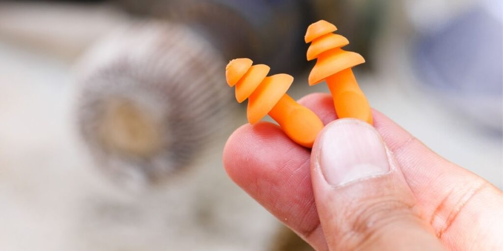 A close up photo of someone holiding a set of orange ear plugs.