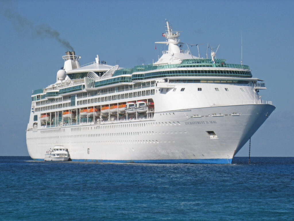 Royal Caribbean’s Enchantment of the Seas cruise ship sailing on calm blue ocean under a clear sky.
