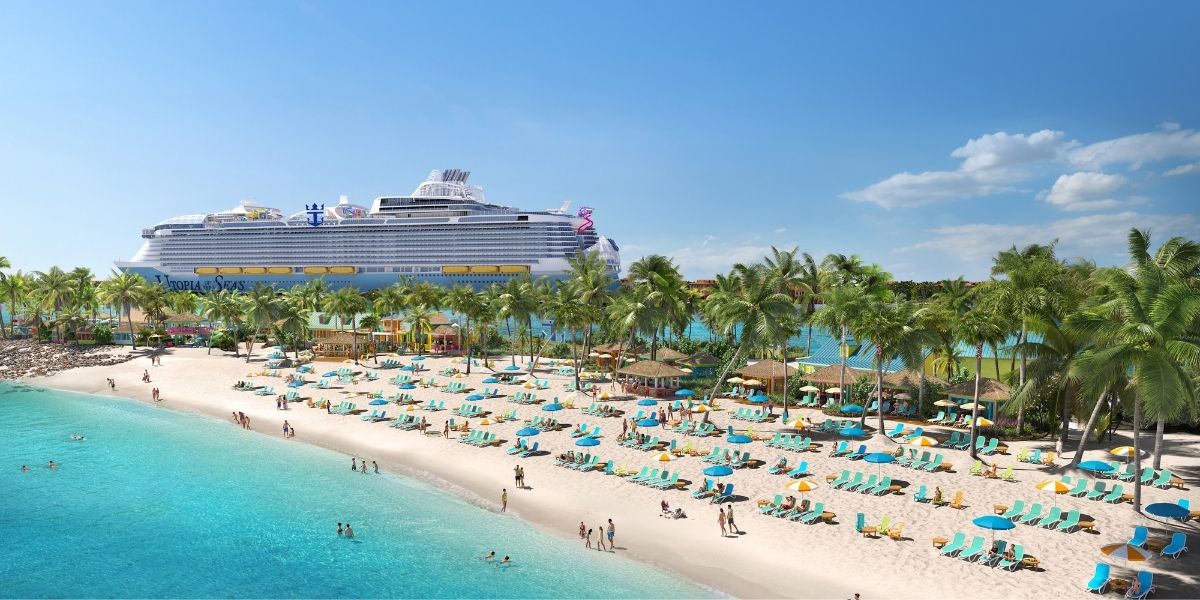 A bright, tropical beach scene at the Family Beach section of the Royal Beach Club in Nassau, showing rows of turquoise lounge chairs and umbrellas along the white sand shoreline. The large Royal Caribbean cruise ship Utopia of the Seas is docked nearby, with lush palm trees and cabanas lining the beach under a clear blue sky.