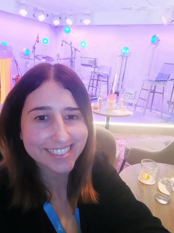 A smiling guest takes a selfie at the 710 Club on P&O’s Iona, with the club's ambient purple lighting and musical stage setup softly blurred in the background, capturing the essence of an enjoyable evening onboard.