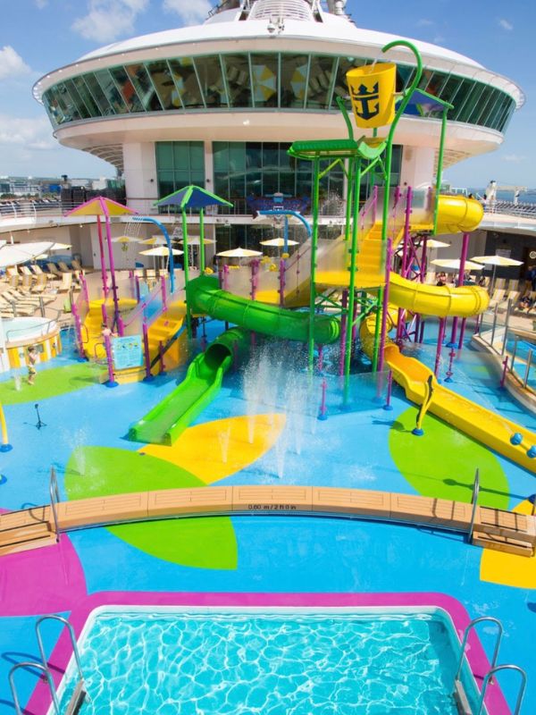 The H2O Zone water park on Royal Caribbean's Freedom Class ship, showcasing a vibrant array of slides and water features with a sparkling pool in the foreground, inviting family fun under the sun.