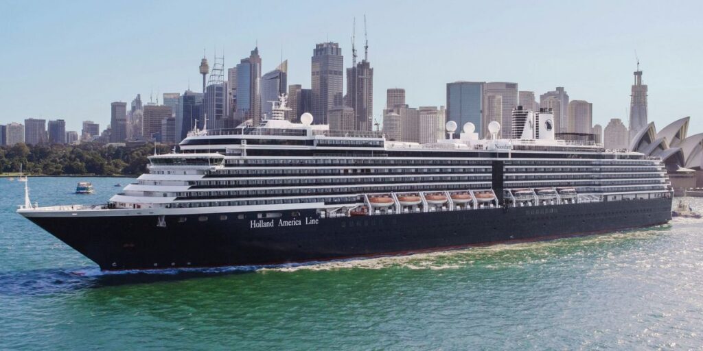 A photo of the MS Nordam, Holland America cruise ship, with tall high rise buildings in the distance.