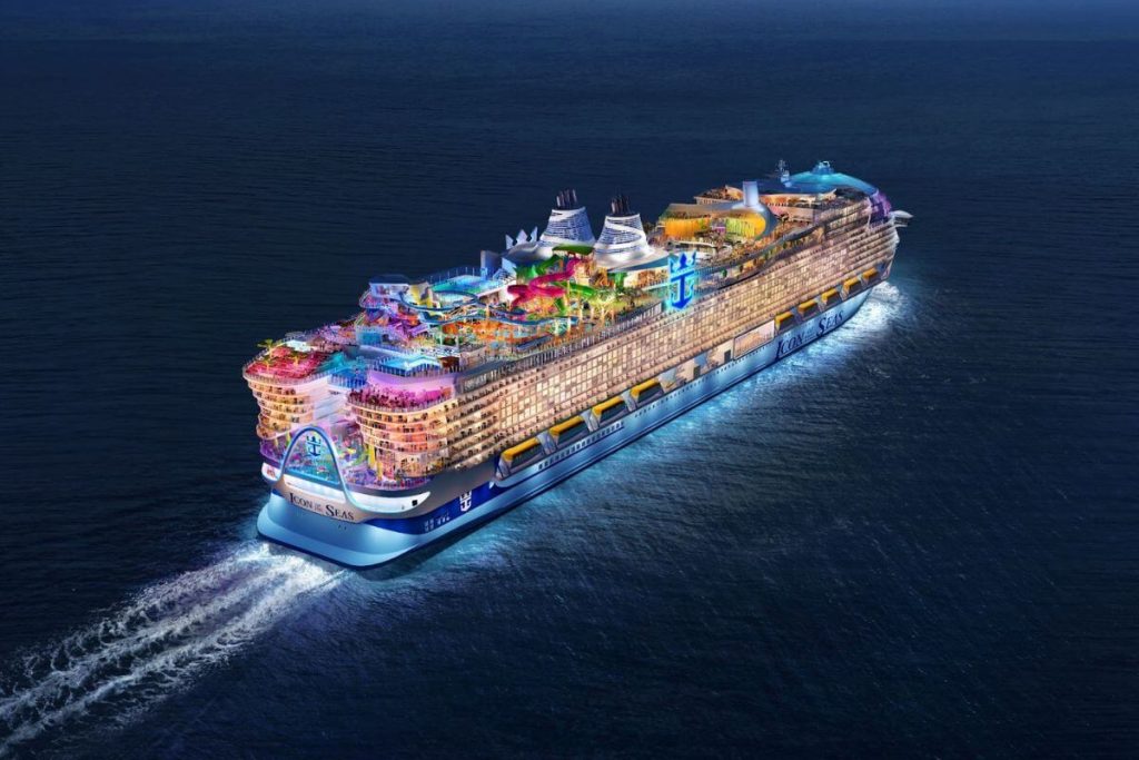 The Icon of the Seas cruise ship is captured cruising on the open sea, showcasing its colorful and vibrant deck activities and amenities against the expansive blue ocean backdrop.