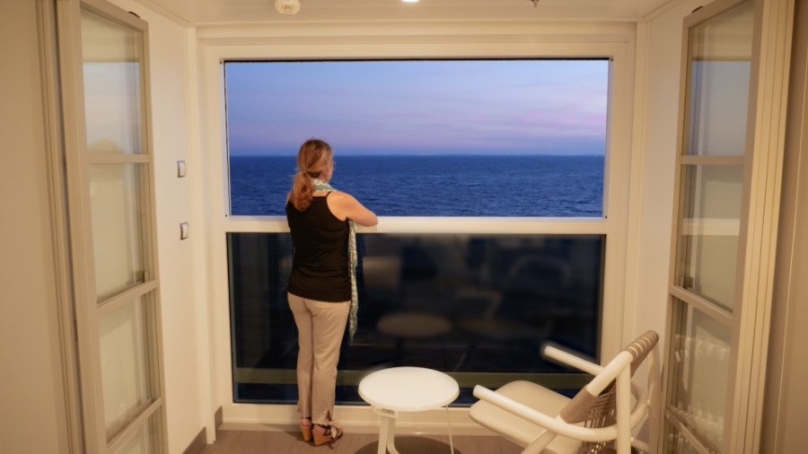 A photo of a woman looking out to sea standing on an Infinite Verandah on a Celebrity cruise ship