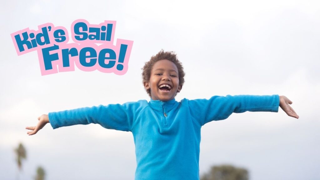 A cheerful child in a bright blue sweater stands outdoors with arms outstretched, smiling widely against a cloudy sky. Bold pink and blue text in the top-left corner reads 'Kid's Sail Free!' promoting a family-friendly cruise deal.