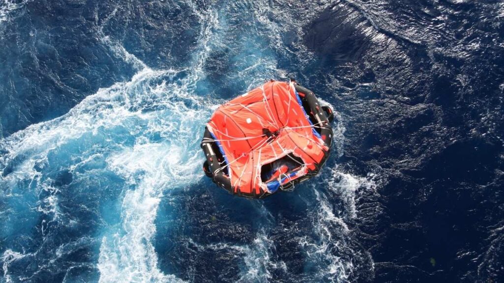An aerial view of an orange life raft in the sea.