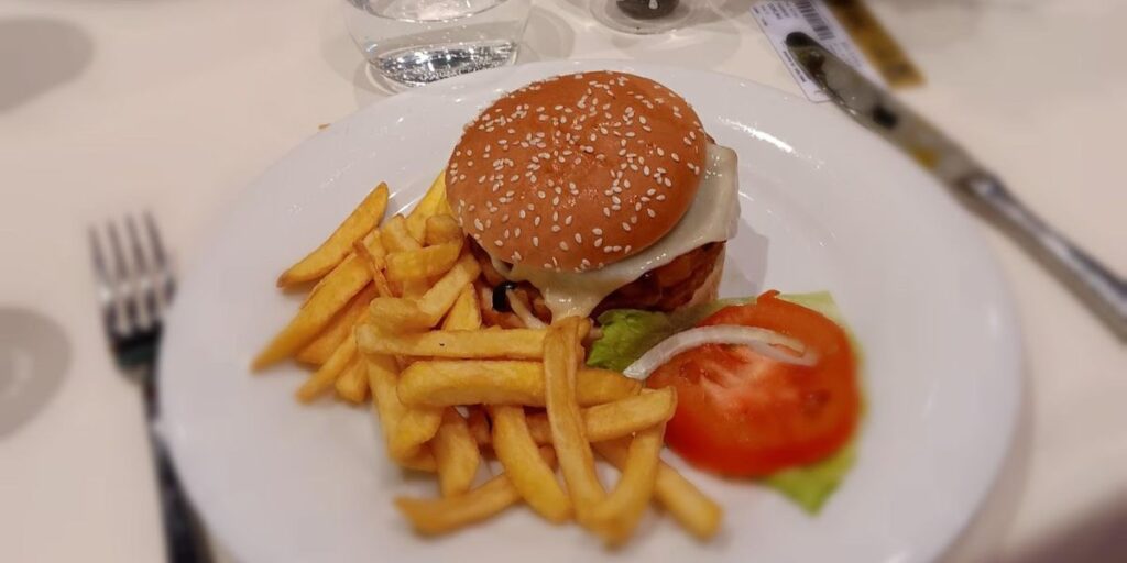 An appetizing burger and fries combo with a slice of fresh tomato.