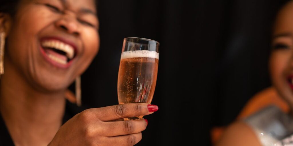 A happy lady holding a glass of champagne with her friend