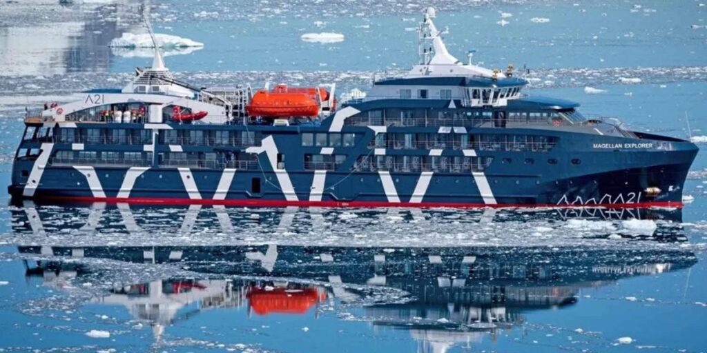 Magellan Discoverer expedition ship navigating icy Antarctic waters, showing its reinforced dark hull, Zodiac boats, and expedition equipment surrounded by floating ice.