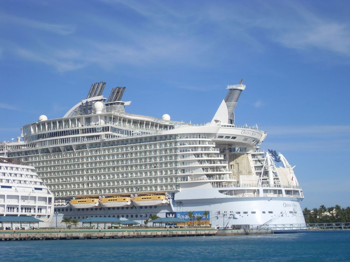The Royal Caribbean Oasis of the Seas cruise ship docked at a port, showcasing its multiple decks and distinctive design under a clear blue sky.