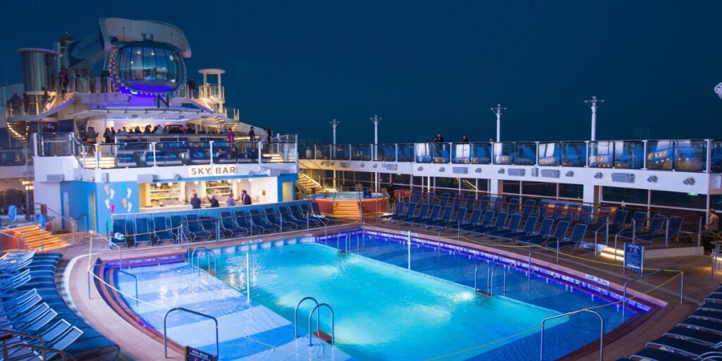 An empty pool deck during the night with the sky bar waiting for guests to party