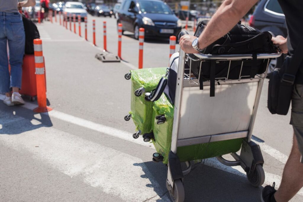 Cruise ship passenger pushing his own luggage, waiting for a porter to help him