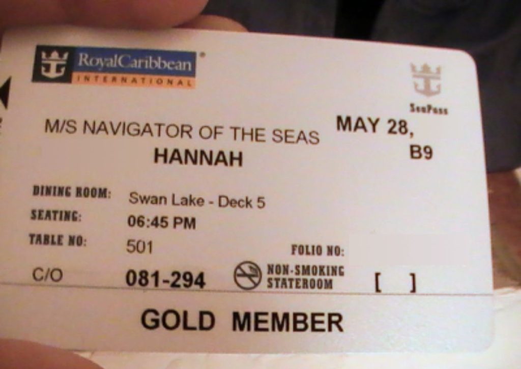 Close-up of a Royal Caribbean Gold Member SeaPass card displaying the ship name 'M/S NAVIGATOR OF THE SEAS', the guest's name 'HANNAH', dining details, and the non-smoking stateroom status.