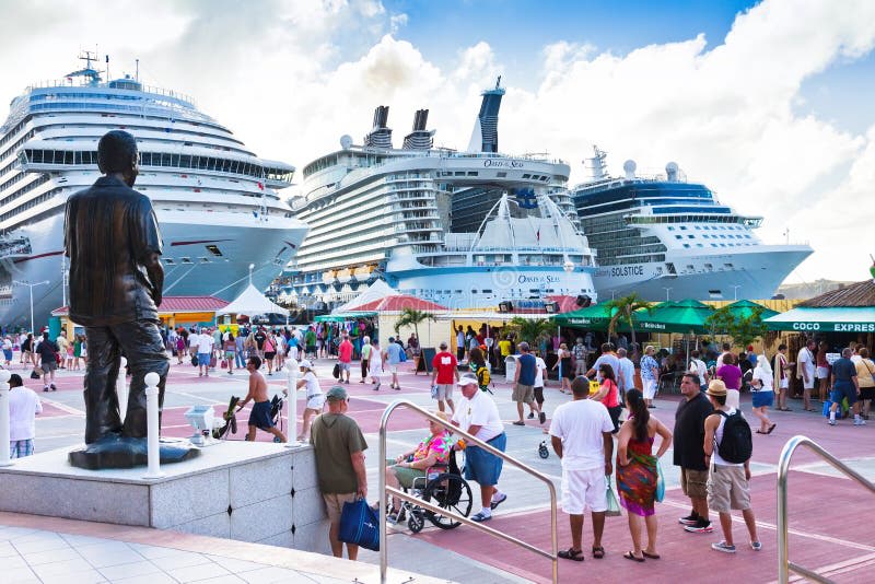 Crowded St. Maarten cruise port with several large ships docked and people walking through the port area.