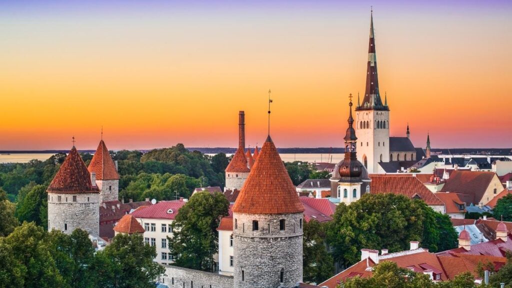 A photo of the town of Tallinn in Estonia, showing th sunsetting on the rooftops and a castle.