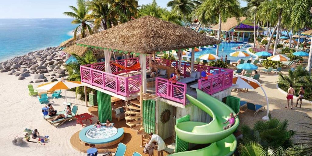 Rendering of the Ultimate Family Cabana at the Royal Beach Club in Nassau, featuring a two-story thatched-roof cabana with bright pink railings, an outdoor spiral slide, a hot tub, and colorful seating. Guests are seen relaxing under umbrellas, with views of the turquoise ocean and a lively pool area surrounded by palm trees in the background.