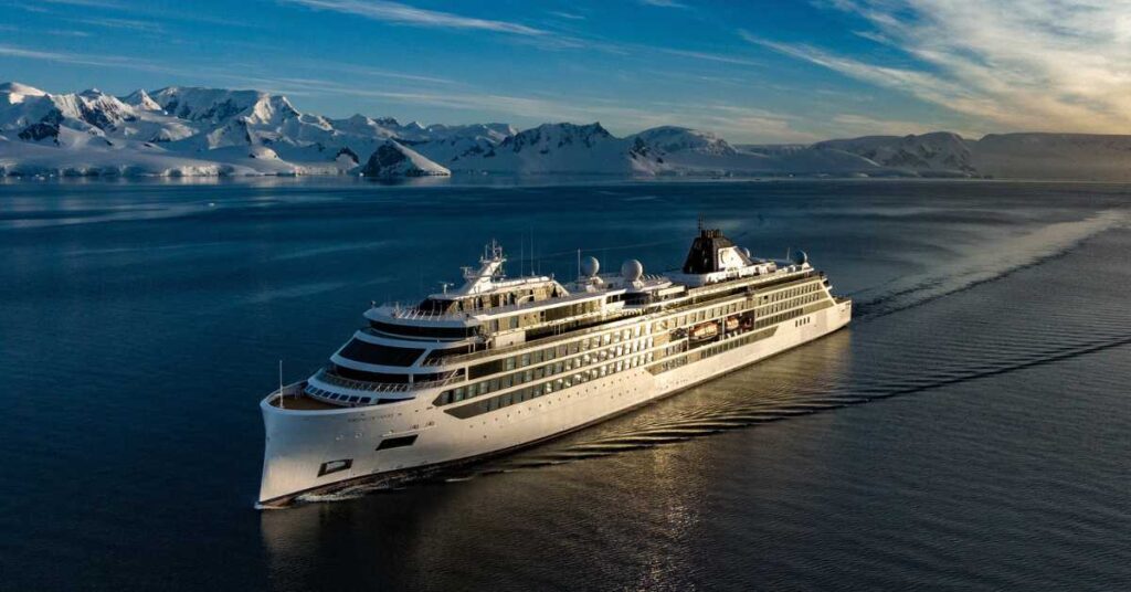 Viking cruise ship sailing past mountains covered in snow