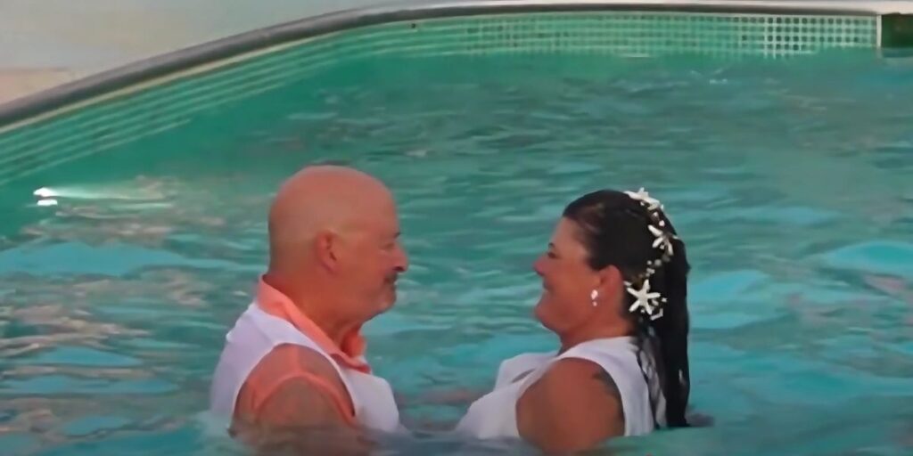 A couple poses in a pool on a cruise.