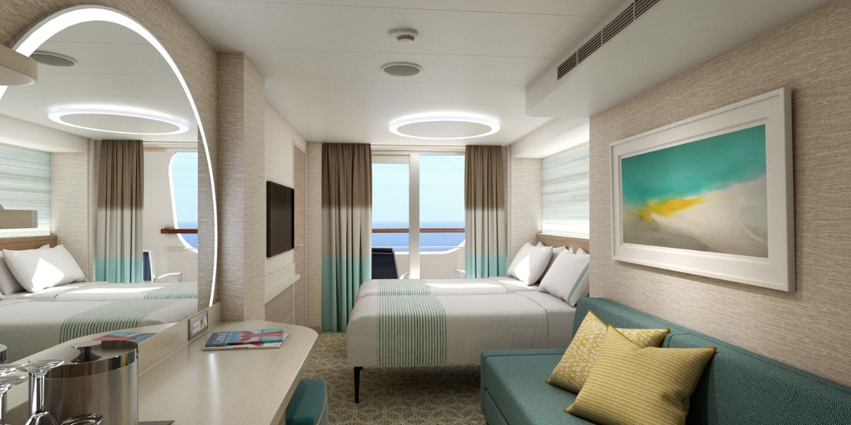 Modern and stylish cruise ship stateroom with a cove balcony, featuring a cozy double bed with turquoise bedding, a matching sofa, and an abstract ocean-themed artwork on the wall. The room is bathed in natural light from the balcony, offering a view of the serene blue sea.