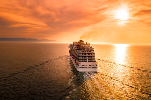 Royal Princess cruise ship at sea during golden sunrise with dramatic orange and gold sky reflecting on the water