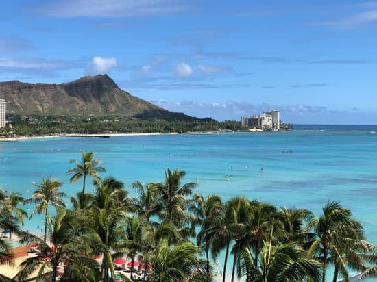A view of Waikiki Beach with turquoise ocean water, palm trees, and Diamond Head in the background.