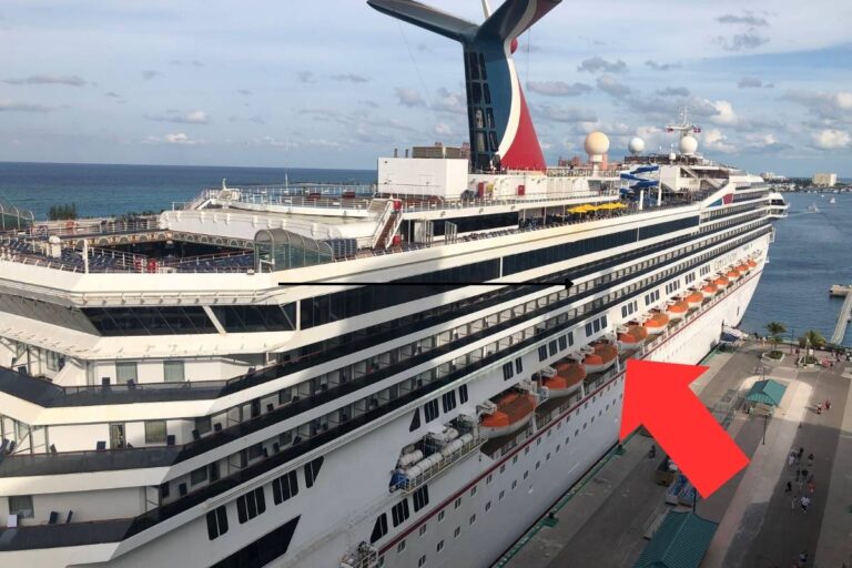 This image shows a Carnival cruise ship docked at a port, with a red arrow pointing to a specific row of balcony cabins. The ship features Carnival's signature red and blue funnel, lifeboats along the lower deck, and various amenities visible on the upper deck. The photo highlights the ship's design and accommodations.