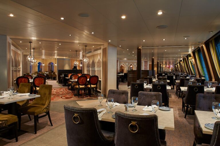 The photo showcases the elegant Marco Polo Restaurant on a Carnival cruise, with its sophisticated decor, plush seating, and well-set dining tables ready to welcome guests for a fine dining experience.