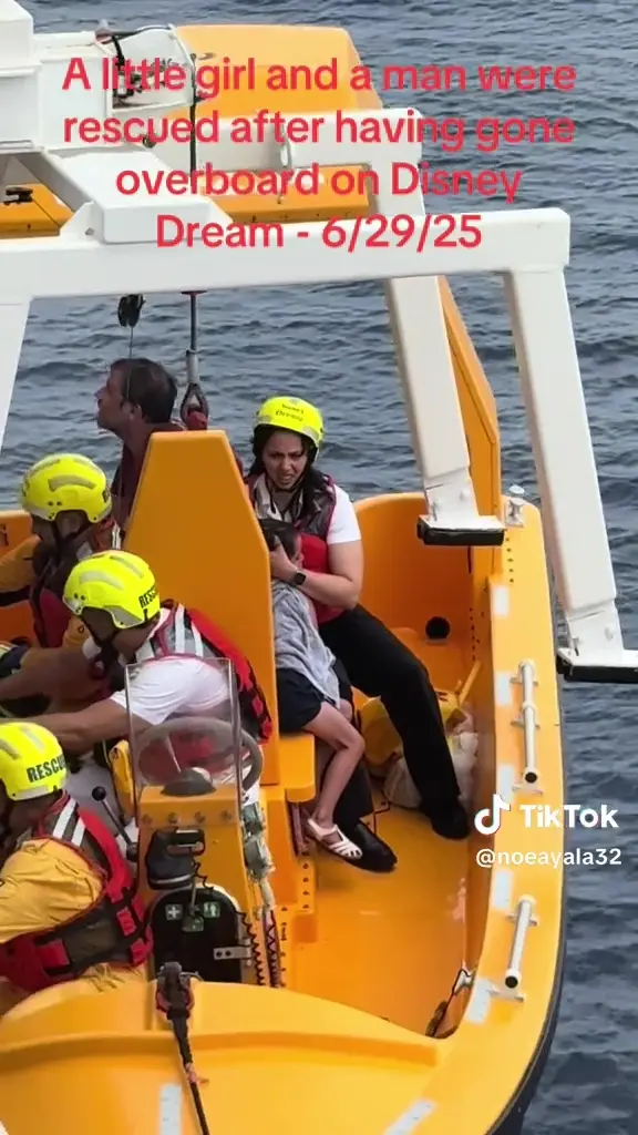 Rescue crew on a bright yellow lifeboat help a man and a young girl who were pulled from the ocean near the Disney Dream cruise ship. The girl sits wrapped in a towel beside rescuers wearing yellow helmets and life vests, with calm blue water in the background. Red overlay text reads, “A little girl and a man were rescued after having gone overboard on Disney Dream - 6/29/25