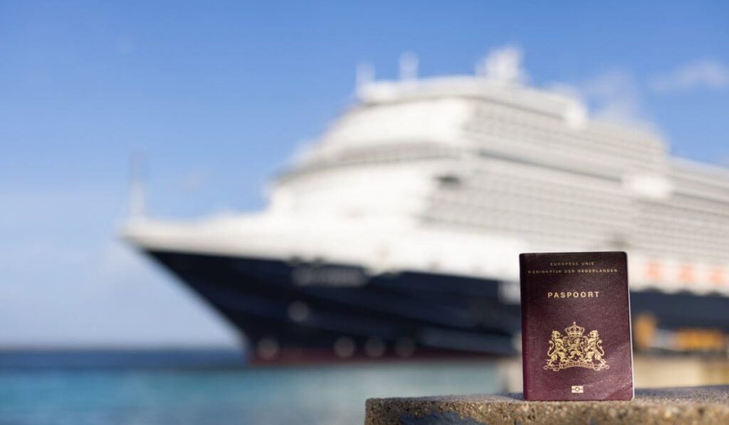 A close-up of a Dutch passport on a ledge with the blurred image of a cruise ship in the background, suggesting international travel and the excitement of exploring new destinations by sea.
