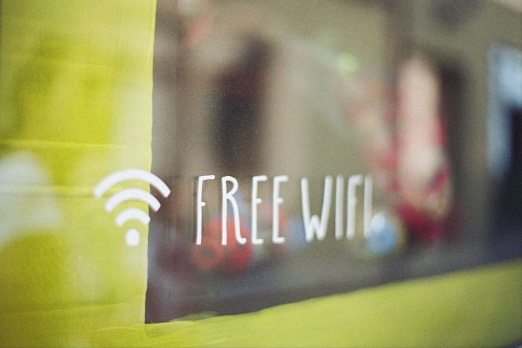 Blurred view through a yellow translucent surface with the words 'FREE WIFI' visible in focus, suggesting a cozy ambiance possibly in a café or public space offering complimentary internet access.