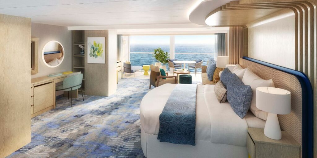 Spacious and elegantly designed grand suite on a cruise ship, with a plush king-size bed, comfortable seating area with ocean view, and modern wooden furnishings, providing a luxurious and serene accommodation experience.