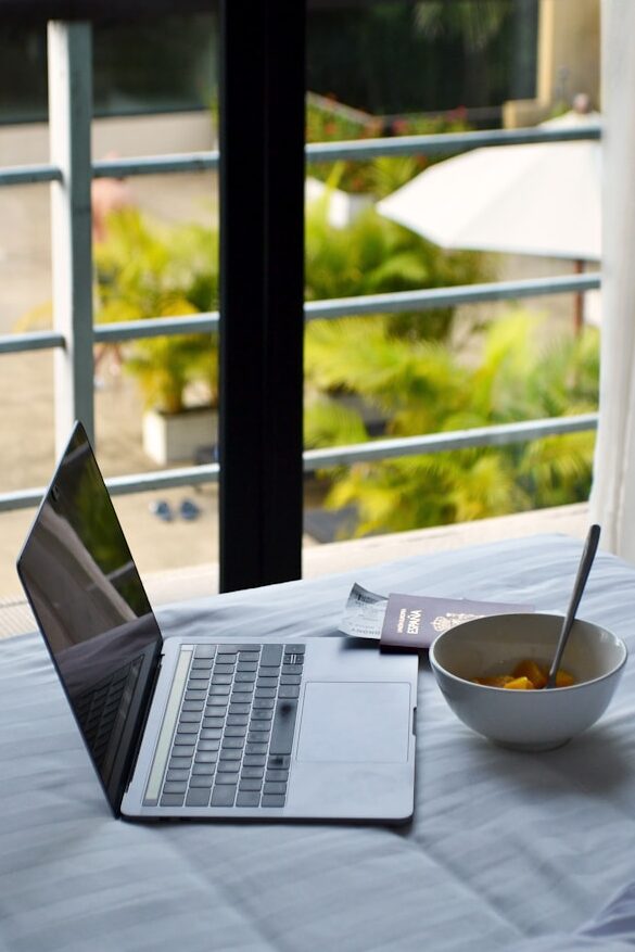 Travel planning setup with a laptop, notebook, and passport on a desk
