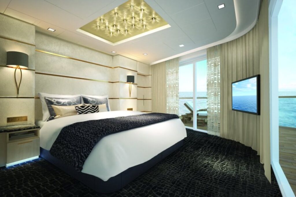 Luxuriously appointed bedroom in the Haven Deluxe Owner's Suite on Norwegian Bliss, featuring a plush bed with a view of the sea through floor-to-ceiling windows and elegant modern decor.