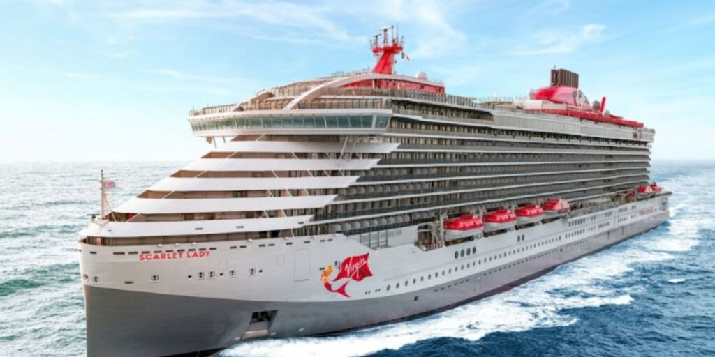Scarlet Lady" cruise ship from Virgin Voyages, its hull adorned with a mermaid logo, cruising on the open sea with a clear sky above and white foam in its wake.