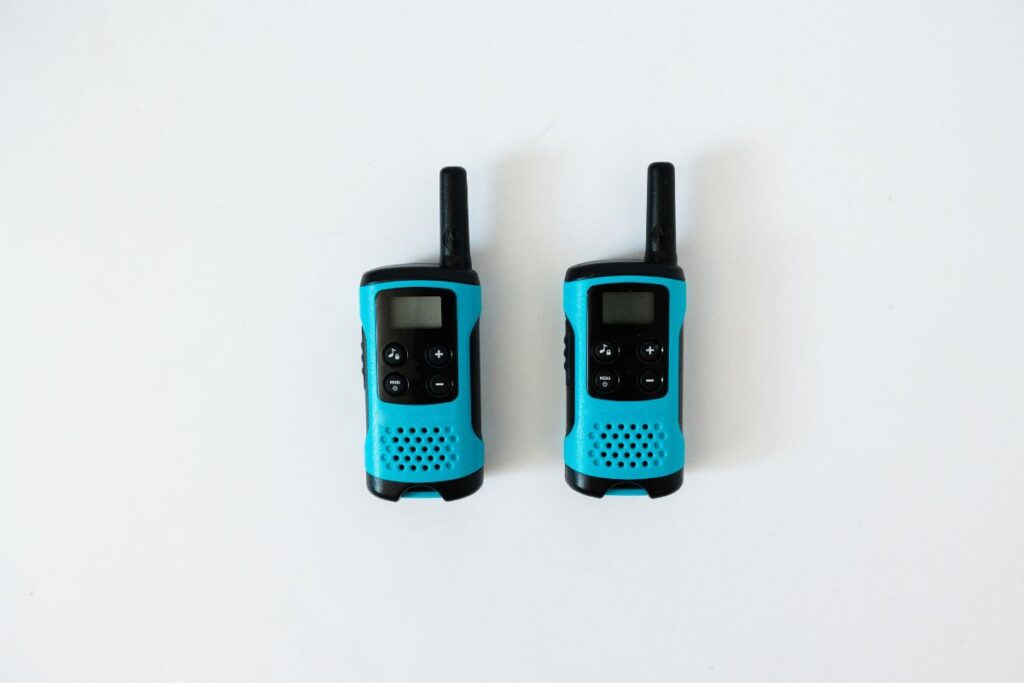 Two turquoise and black walkie-talkies with antennas up, placed side by side on a white background, showcasing the buttons and speaker design.