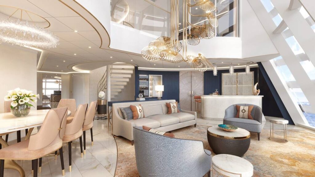 Luxurious living area of the Wish Tower Suite on Disney Wish, featuring modern decor with golden accents, an elegant chandelier, plush seating, and a sweeping staircase against large windows with a sea view.